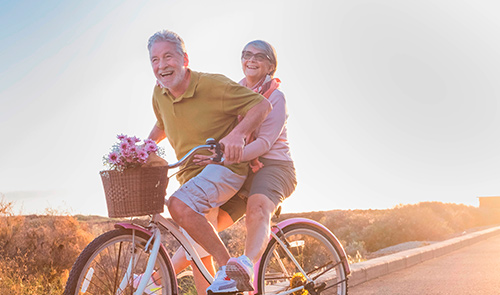 Pareja montando bicicleta disfrutando de la tranquilidad de tener su dinero en cuenta pensión diamante